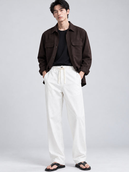 Model wearing DILI white linen-cotton trousers with dark overshirt and sandals