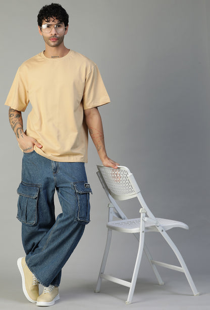 Man wearing a beige oversized cotton T-shirt with blue jeans