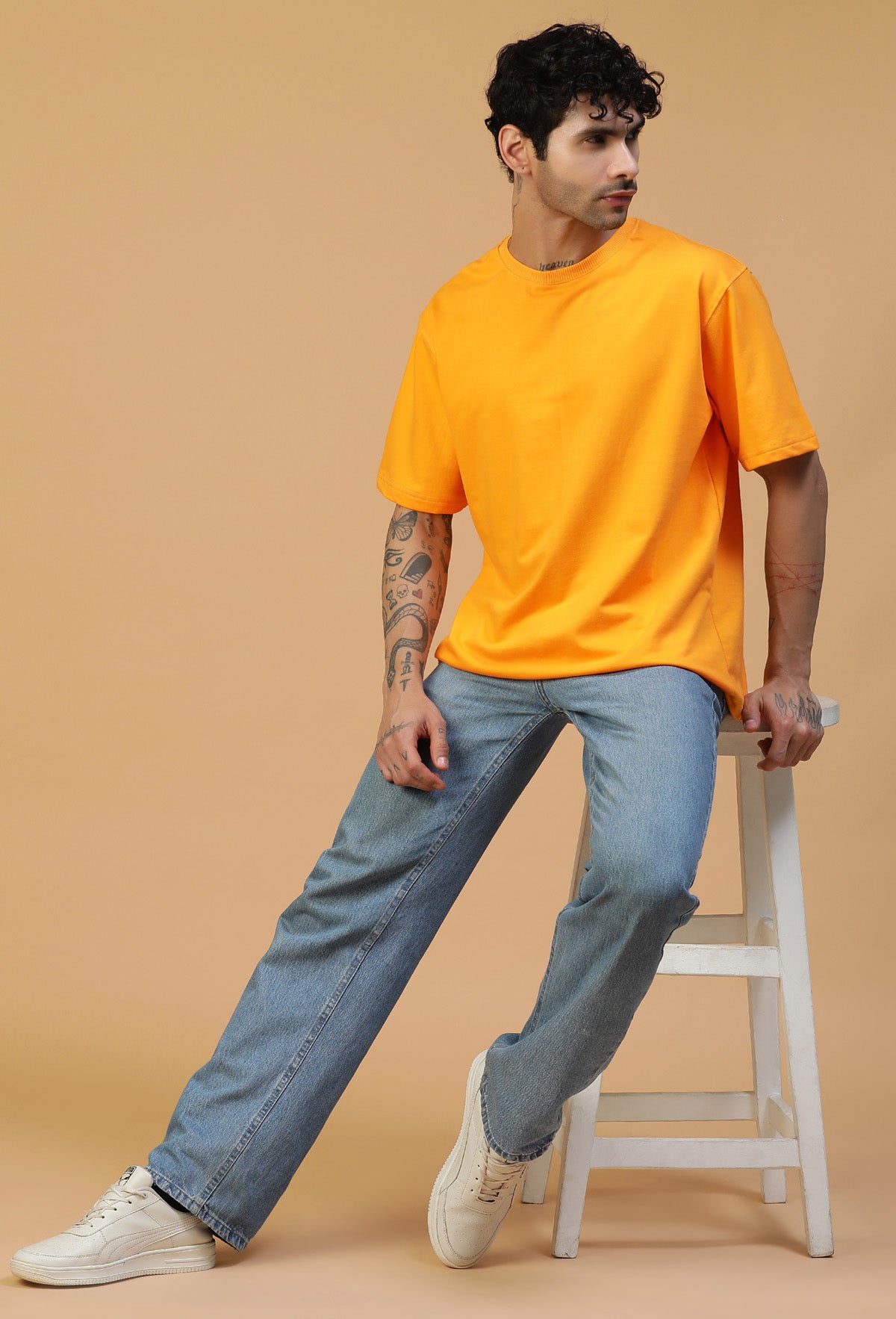 Man wearing a mustard oversized cotton T-shirt with blue jeans