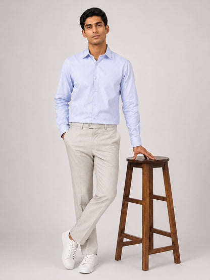Men's sky blue cotton shirt styled with beige trousers, full-length view